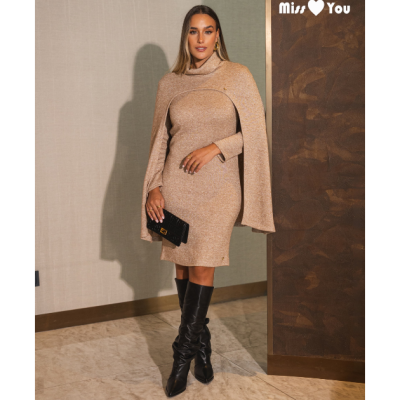 Mulher com vestido bege de malha e capa, botas pretas e carteira preta