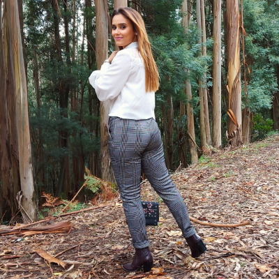 Mulher na floresta com camisa branca, calças xadrez e botins pretos