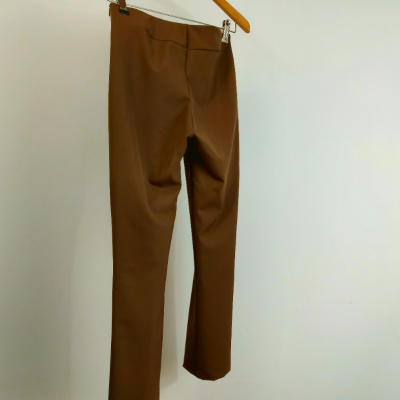 Calças castanhas penduradas num cabide na parede