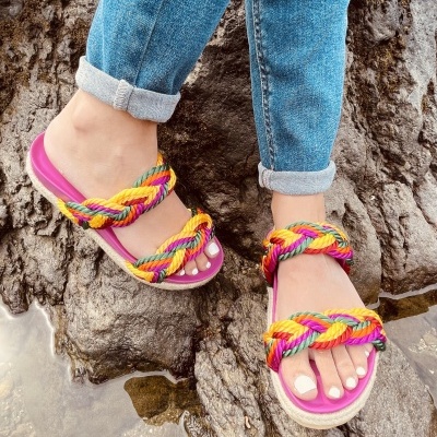 Sandálias com tiras trançadas coloridas sobre rochas