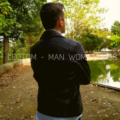 Homem de costas com jaqueta preta junto a canal com árvores e ponte