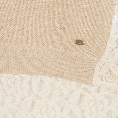 Peça de vestuário bege em malha e tecido rendado branco com etiqueta metálica.