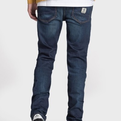 Calças de ganga azul escuro vistas de trás com ténis Adidas e camisola amarela