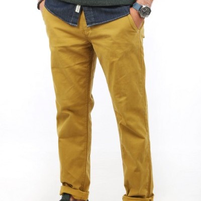 Calças amarelo mostarda com bainhas viradas, camisa azul escura, camisola cinza e ténis verdes Nike