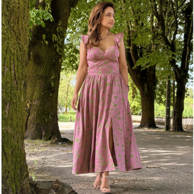 Vestido longo rosa com pontos verdes e folhos usado por mulher em parque