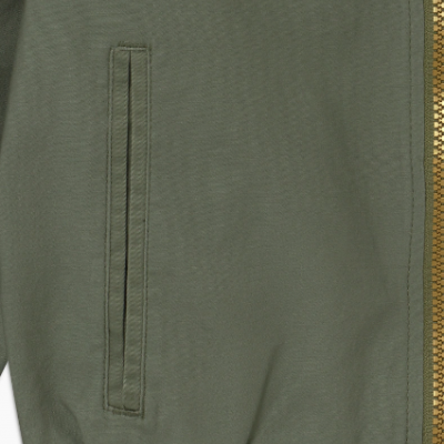 Detalhe parte inferior de casaco bomber verde com bolso, fecho dourado e punho elástico