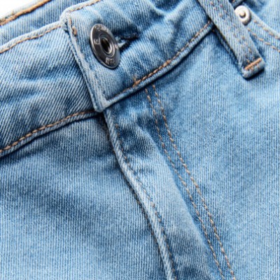 Close-up de jeans azuis com botão metálico e costuras castanhas