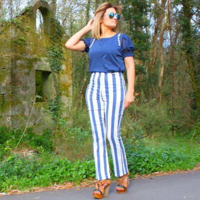 Mulher com t-shirt azul e calças de riscas azuis e brancas em ambiente exterior