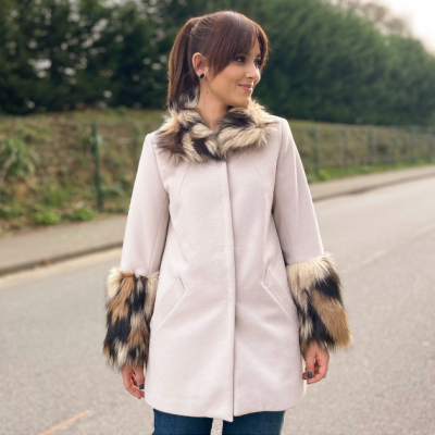 Mulher com casaco bege de pelo nas mangas e gola em ambiente exterior