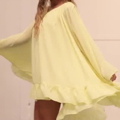 Mulher a usar vestido amarelo solto com folhos num espaço interior