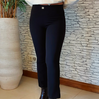 Calças pretas justas com botão prateado em ambiente interior