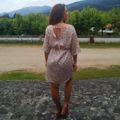 Vestido curto de tecido leve cor-de-rosa com bolinhas coloridas e laço nas costas