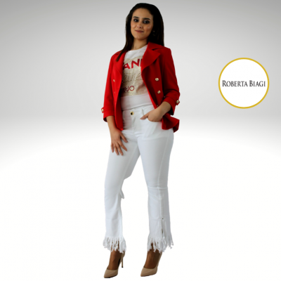 Mulher com blazer vermelho, t-shirt branca, calças brancas com franjas e sapatos bejes