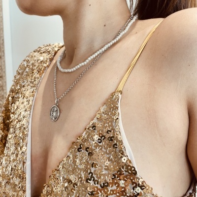 Vestido com lantejoulas douradas, colares de pérolas e pendente redondo