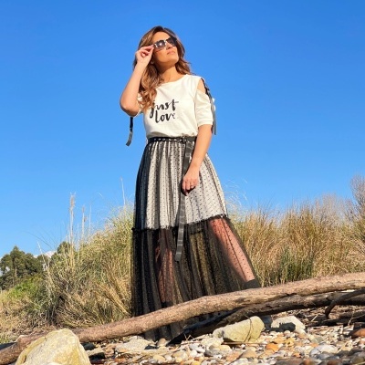 Mulher com t-shirt branca 'Just Love' e saia preta transparente em ambiente natural