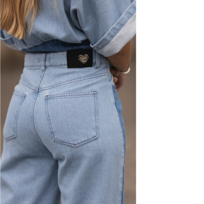 Calças de ganga azul claro com bolso traseiro e etiqueta preta com coração dourado e texto MILA