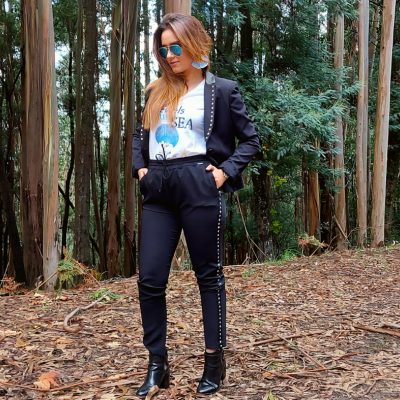 mulher com conjunto preto e camiseta branca em floresta