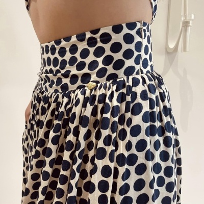 Saia plissada branca com bolas pretas e cintura alta com botão dourado