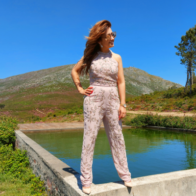 Mulher com macacão rosa de padrão floral junto a tanque de água exterior