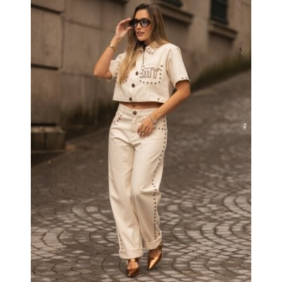Mulher com conjunto bege de camisa cropped e calças largas com tachas