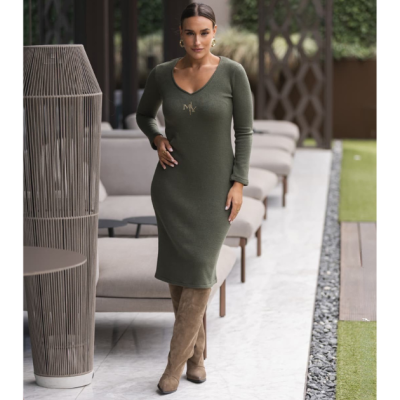Vestido verde-oliva ajustado com logótipo, botas castanhas, ambiente exterior com cadeiras cinzentas.