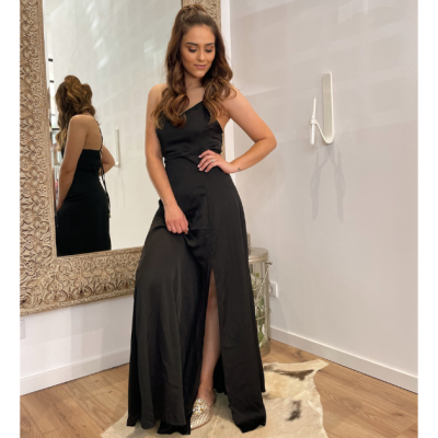 Vestido longo preto com fenda e alças finas em ambiente interior com espelho e chão de madeira