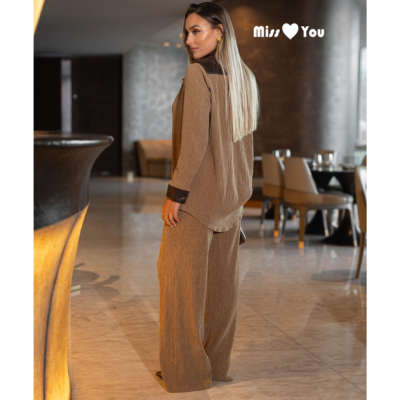 Conjunto castanho de senhora com camisa e calças largas num ambiente interior moderno