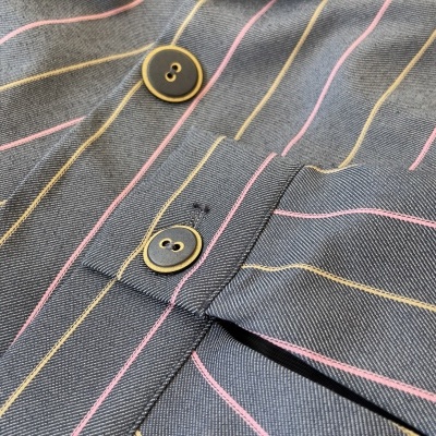 Casaco cinzento riscado com botões pretos e detalhes amarelos e cor-de-rosa