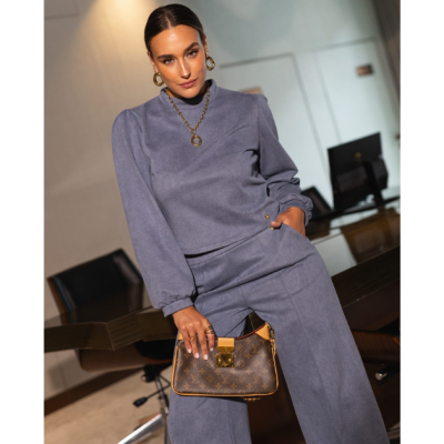 Mulher com conjunto cinzento macio e mala Louis Vuitton castanha com padrão monograma