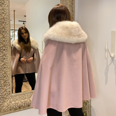 Capa cor-de-rosa com gola de pele branca vista de costas em ambiente interior