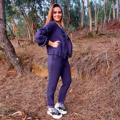Mulher com conjunto desportivo azul escuro numa floresta com ténis brancos