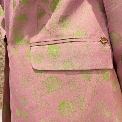 Casaco rosa com padrão floral verde e botão dourado