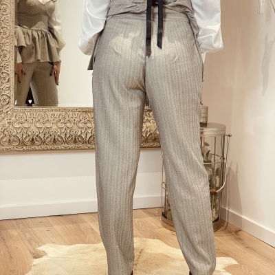 Calças cinza com riscas usadas por mulher em ambiente interior