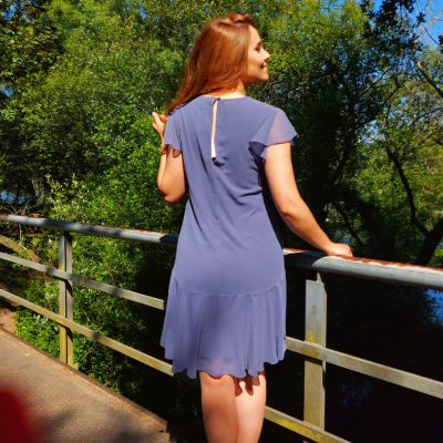 Vestido azul claro com manga curta visto de costas num ambiente natural junto a um rio