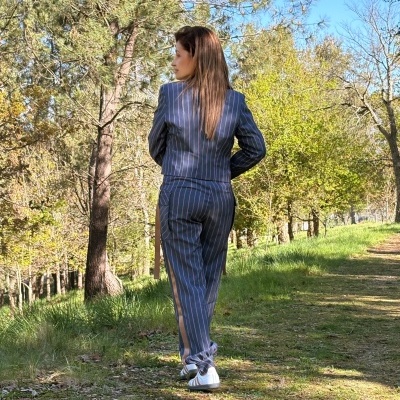 Mulher vista de costas com fato riscado cinzento e sapatos brancos ao ar livre