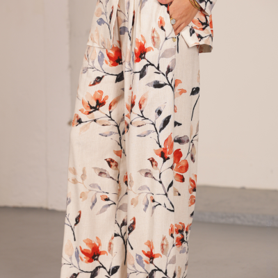 Blazer e calças largas com padrão floral em tons de laranja, negro e cinza sobre fundo bege.