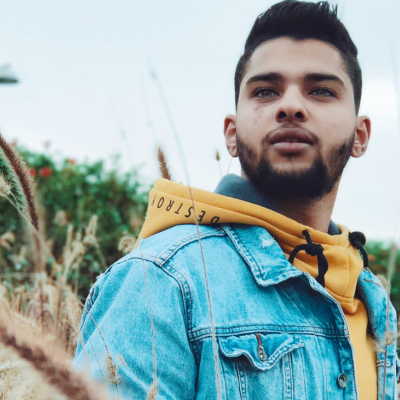 Homem com casaco de ganga azul claro e capuz amarelo em ambiente natural exterior