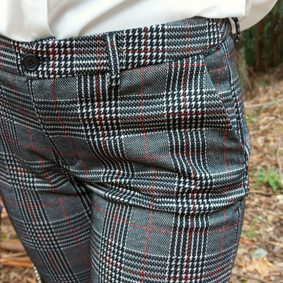 Calças xadrez cinza, preto e vermelho, com bolso e botão, em ambiente natural