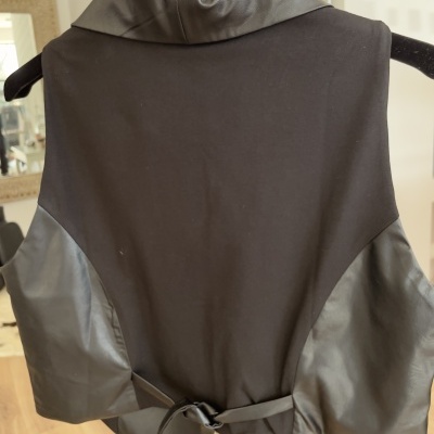 Colete preto com detalhes em couro e cinto na parte traseira