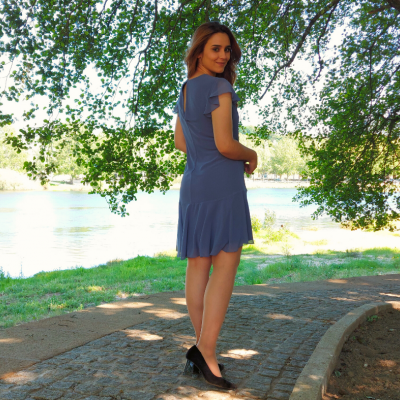 Mulher com vestido azul curto num passeio ao ar livre junto a um rio