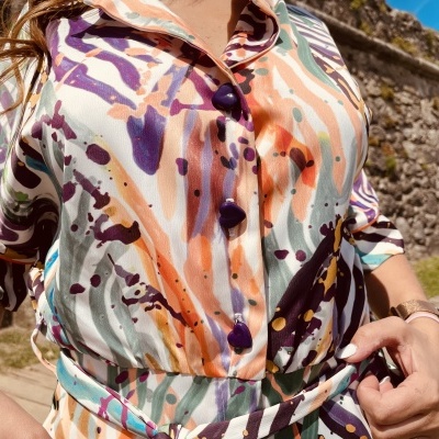 Vestido camisola colorido com botões e cinto ao ar livre junto a muro de pedra