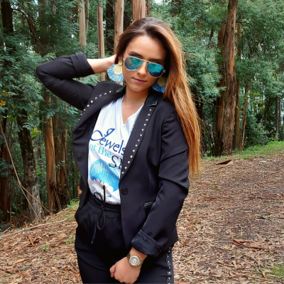 Mulher com óculos de sol e blazer preto em floresta