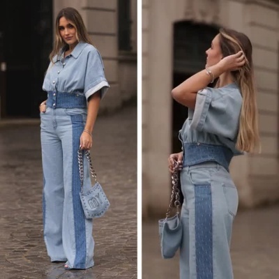 Mulher a usar conjunto denim azul com calças largas e camisa, segurando mala azul com corrente
