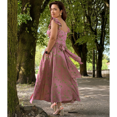 Vestido comprido rosa com padrão de bolinhas verdes e laço na cintura ao ar livre