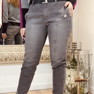 Calças de ganga cinzentas com cinto preto e flor decorativa branca num ambiente interior