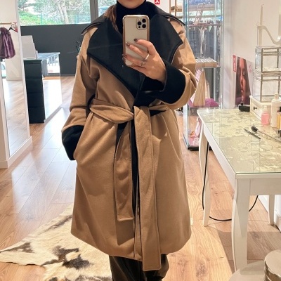 Casaco comprido feminino camel com detalhes pretos e cinto, pessoa a tirar selfie num espelho