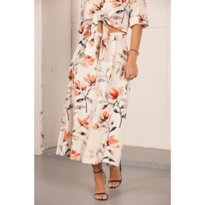 Conjunto feminino floral com saia midi e camisa amarrada, tecido leve e sandálias pretas.