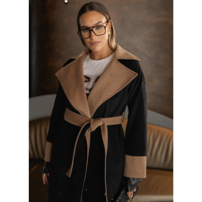 Mulher com casaco preto e castanho com cinto e óculos grandes em interior