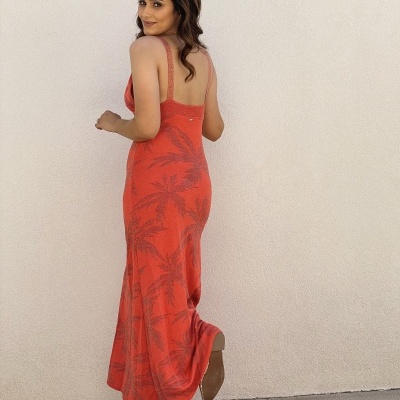 Mulher com vestido comprido vermelho com padrão de palmeiras
