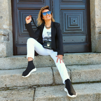 Mulher sentada em degraus com roupa casual e bolsa preta MONNICK